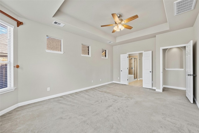 unfurnished bedroom with ceiling fan, light colored carpet, and a raised ceiling