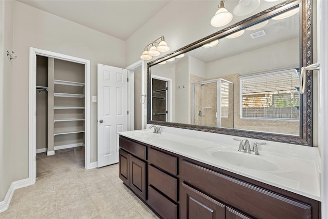 bathroom with a shower with door, vanity, and tile patterned floors