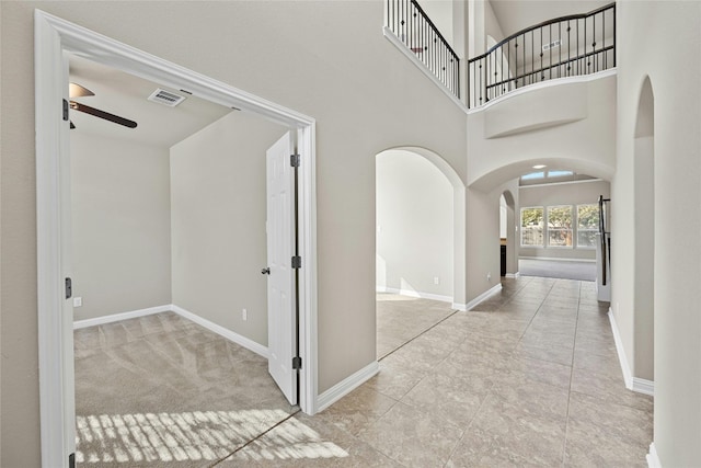 hall with a towering ceiling and light colored carpet