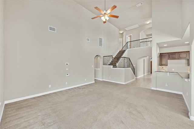 unfurnished living room featuring light colored carpet, high vaulted ceiling, and ceiling fan