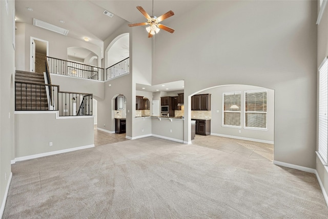 unfurnished living room featuring light colored carpet, high vaulted ceiling, and ceiling fan