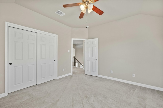 unfurnished bedroom with a closet, ceiling fan, light colored carpet, and vaulted ceiling