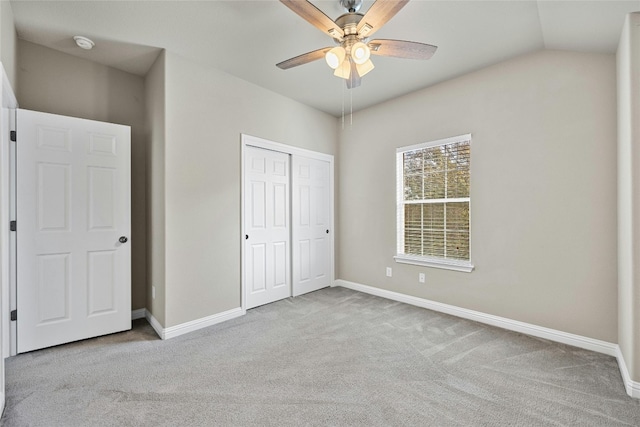 unfurnished bedroom featuring vaulted ceiling, light carpet, a closet, and ceiling fan