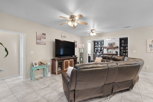 tiled living room featuring a textured ceiling, built in shelves, and ceiling fan