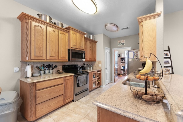 kitchen featuring backsplash, appliances with stainless steel finishes, light tile patterned flooring, and light stone counters