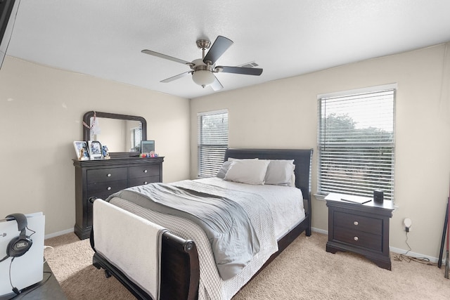 carpeted bedroom featuring multiple windows and ceiling fan