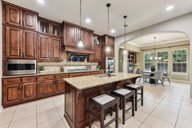 kitchen featuring decorative backsplash, a center island with sink, a breakfast bar area, decorative light fixtures, and stainless steel appliances