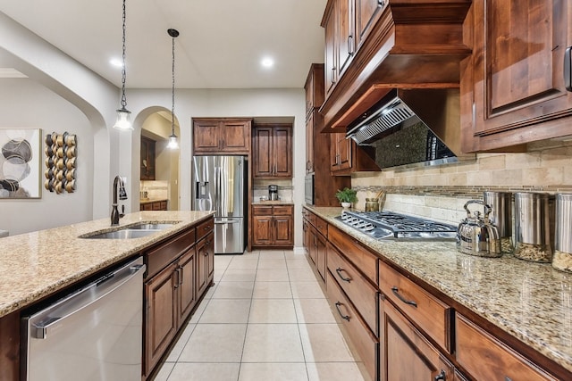 kitchen with decorative backsplash, hanging light fixtures, stainless steel appliances, sink, and light stone countertops