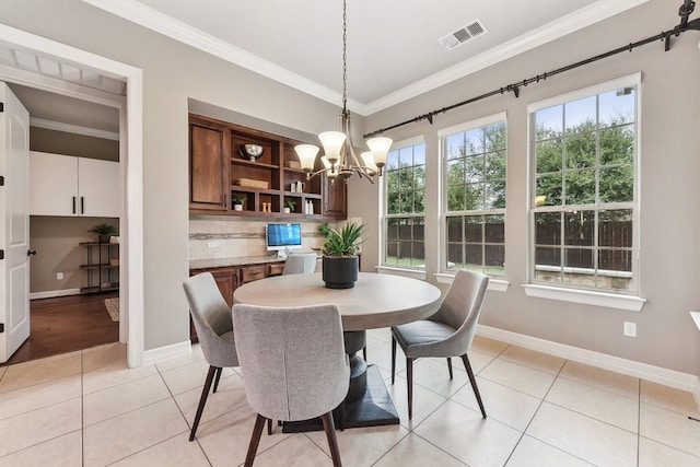 dining space featuring light tile patterned flooring, ornamental molding, and an inviting chandelier