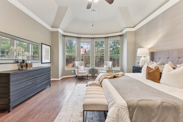 bedroom with crown molding, wood-type flooring, a tray ceiling, and ceiling fan