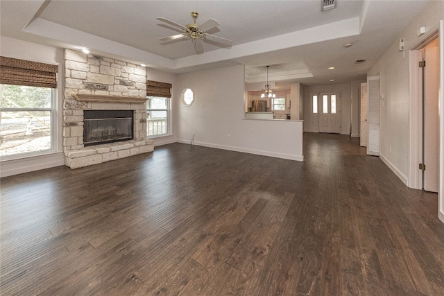 unfurnished living room with dark hardwood / wood-style flooring, a tray ceiling, and plenty of natural light