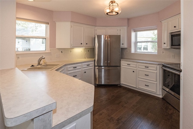 kitchen featuring stainless steel appliances, white cabinetry, dark hardwood / wood-style flooring, decorative backsplash, and sink