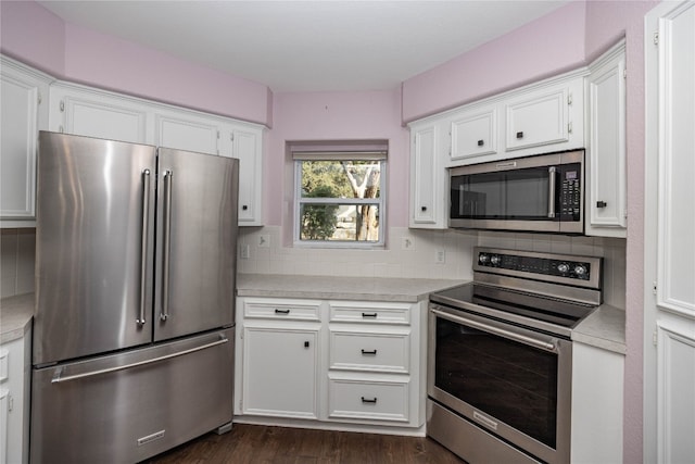 kitchen with white cabinets, appliances with stainless steel finishes, backsplash, and dark hardwood / wood-style flooring