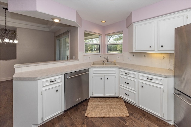 kitchen with pendant lighting, kitchen peninsula, stainless steel appliances, and white cabinets