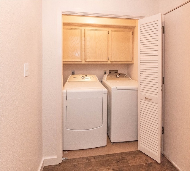 washroom with dark wood-type flooring, cabinets, and washing machine and clothes dryer