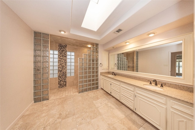 bathroom featuring vanity, a healthy amount of sunlight, a tile shower, and a skylight