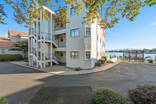 view of property featuring central air condition unit and a water view