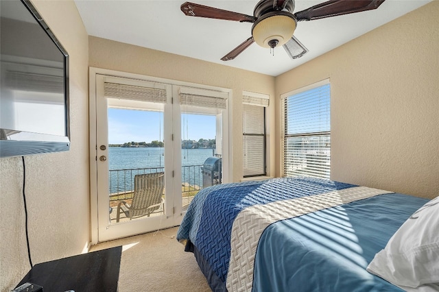 bedroom with access to exterior, light carpet, a water view, and ceiling fan