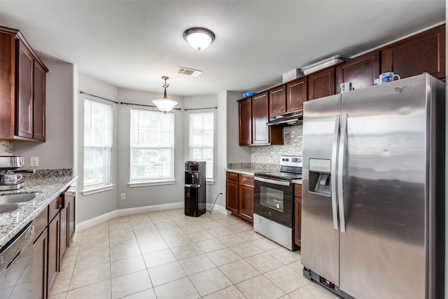 kitchen featuring a healthy amount of sunlight, stainless steel appliances, light stone counters, and pendant lighting