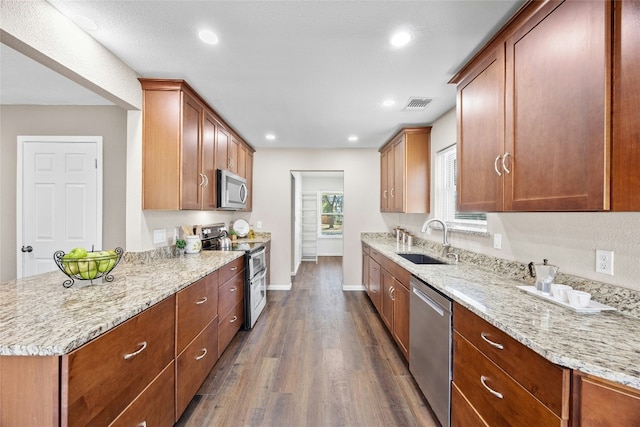 kitchen featuring light stone countertops, sink, dark wood-type flooring, and appliances with stainless steel finishes