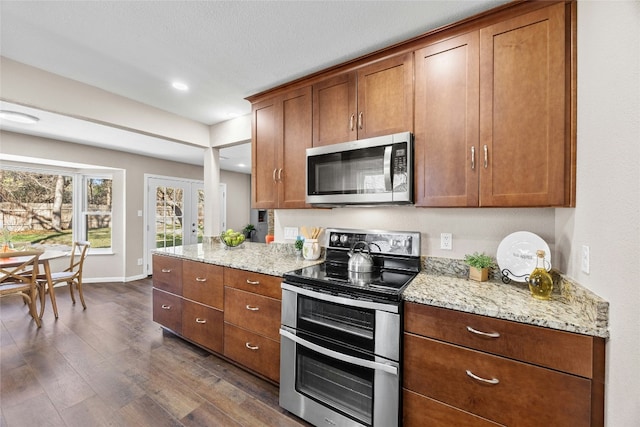 kitchen with light stone countertops, stainless steel appliances, and dark wood-type flooring