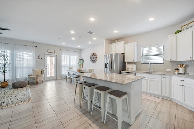 kitchen with white cabinetry, stainless steel appliances, decorative backsplash, and a kitchen island