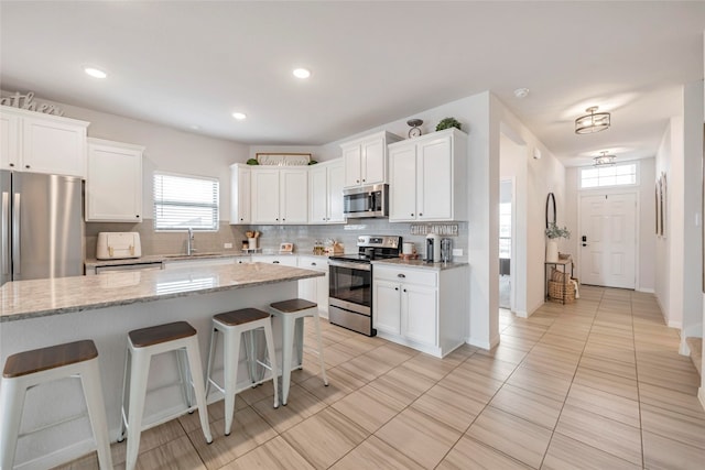 kitchen with sink, a center island, appliances with stainless steel finishes, and white cabinets