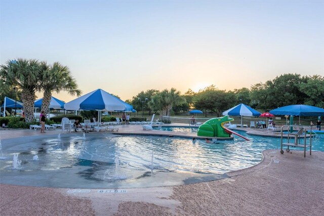 335 Lombardia Dr Unit 19E, Austin, TX 78734 - pool at dusk featuring a community pool, a water slide, and a patio