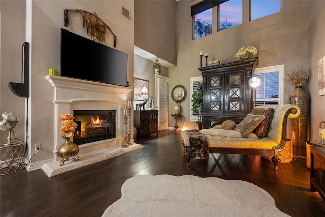 335 Lombardia Dr Unit 19E, Austin, TX 78734 - living room with visible vents, a glass covered fireplace, wood finished floors, a towering ceiling, and baseboards