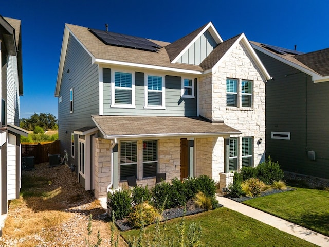 view of front of home featuring central AC unit, solar panels, covered porch, and a front lawn