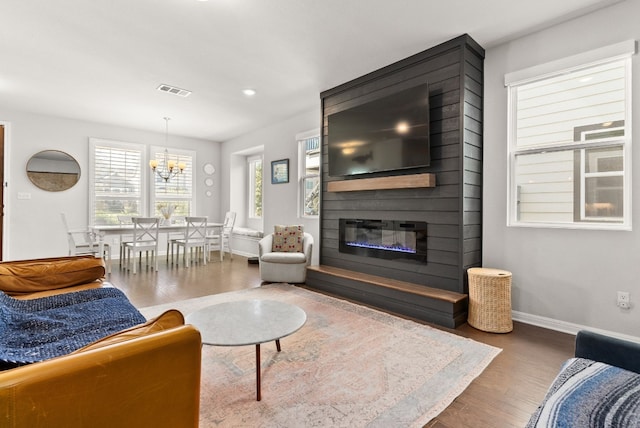 living room featuring hardwood / wood-style flooring, a fireplace, and an inviting chandelier