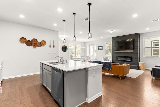 kitchen with dishwasher, a kitchen island with sink, sink, hanging light fixtures, and a fireplace