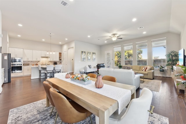 dining area featuring ceiling fan with notable chandelier and dark hardwood / wood-style flooring