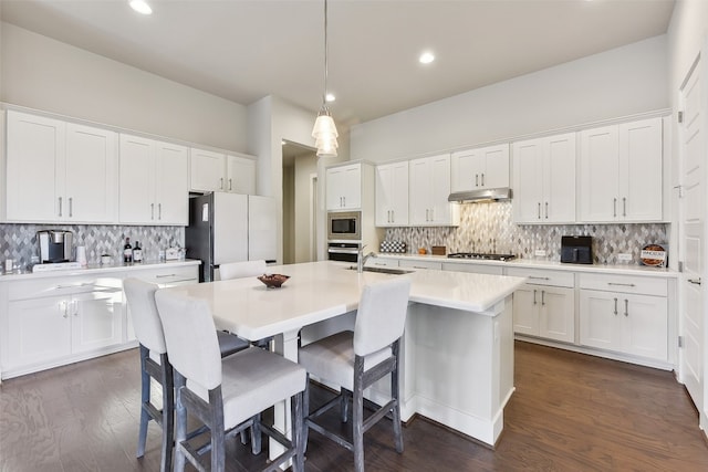 kitchen with white cabinetry, stainless steel appliances, hanging light fixtures, and dark hardwood / wood-style floors