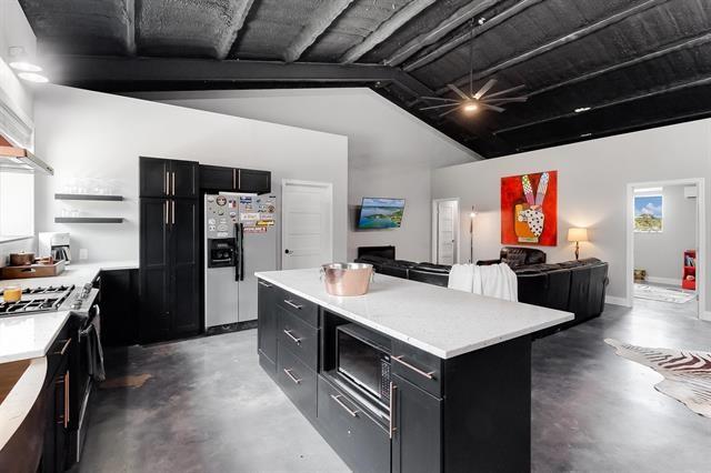 kitchen with a kitchen island, stainless steel appliances, and vaulted ceiling