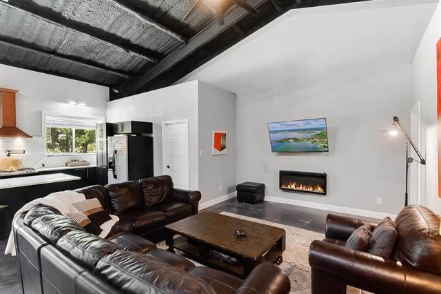 living room with beam ceiling, high vaulted ceiling, and concrete floors