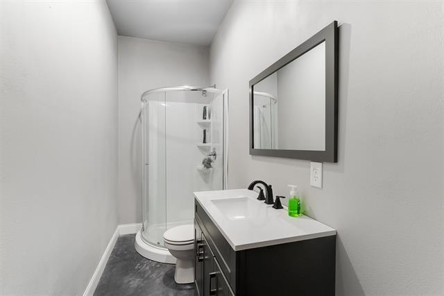 bathroom with vanity, toilet, and a shower with door