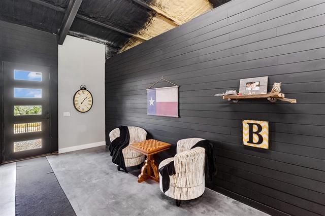 living area featuring wooden walls and concrete floors