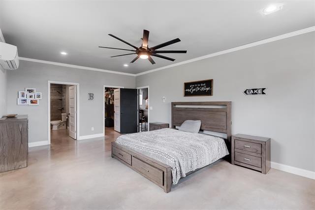 bedroom featuring connected bathroom, ceiling fan, a walk in closet, a closet, and ornamental molding