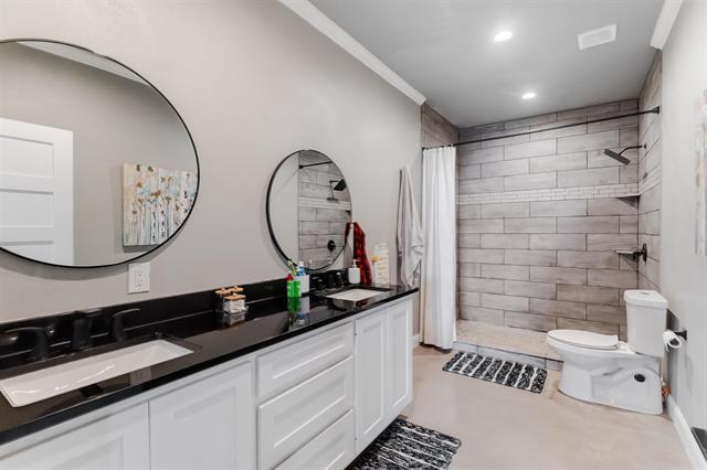 bathroom with vanity, toilet, ornamental molding, and walk in shower