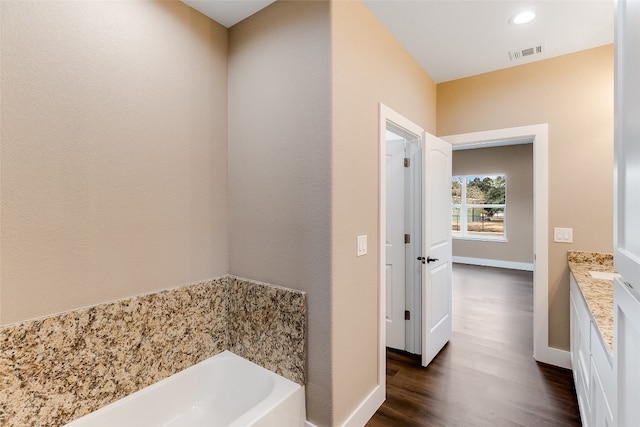 bathroom with vanity, hardwood / wood-style flooring, and a washtub