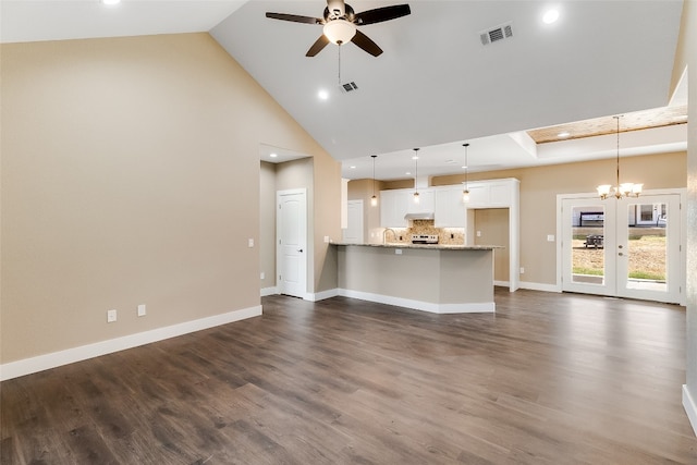 unfurnished living room with sink, dark wood-type flooring, ceiling fan with notable chandelier, and high vaulted ceiling