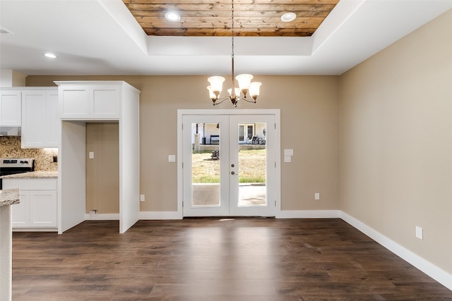 unfurnished dining area with dark wood-type flooring, a raised ceiling, french doors, and wooden ceiling