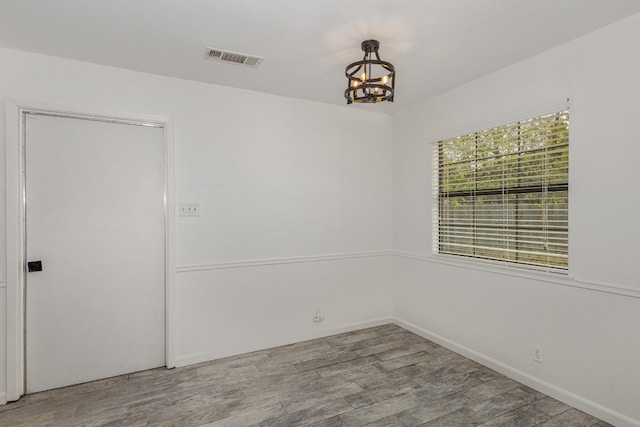 spare room with light hardwood / wood-style floors and a chandelier