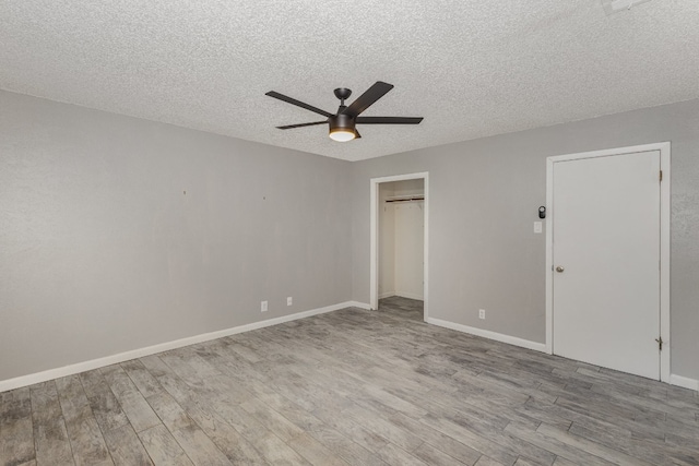 unfurnished bedroom featuring a closet, ceiling fan, a textured ceiling, and light wood-type flooring