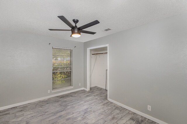 unfurnished bedroom with a closet, ceiling fan, a textured ceiling, and light wood-type flooring