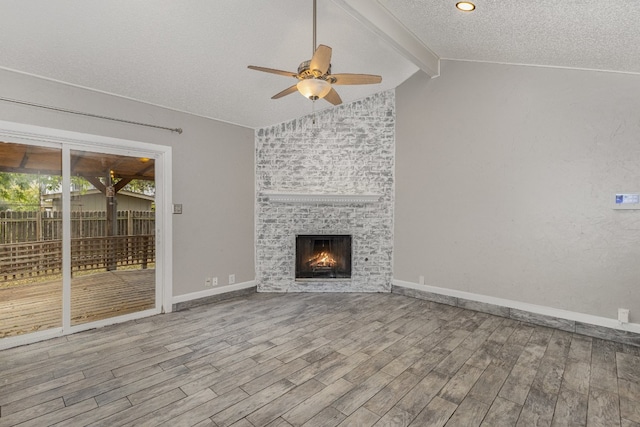 unfurnished living room with light hardwood / wood-style floors, vaulted ceiling with beams, a fireplace, and ceiling fan