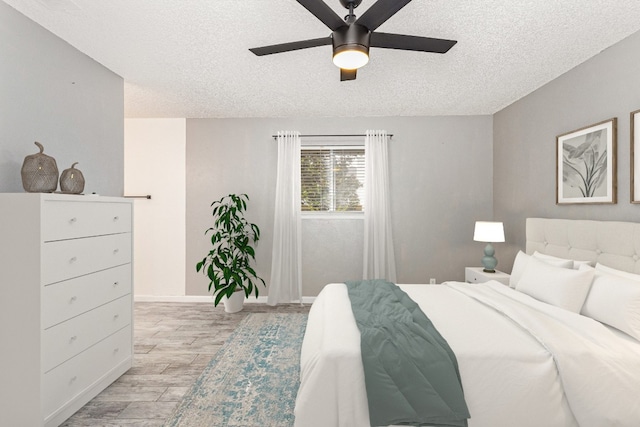 bedroom featuring a textured ceiling, light wood-type flooring, and ceiling fan