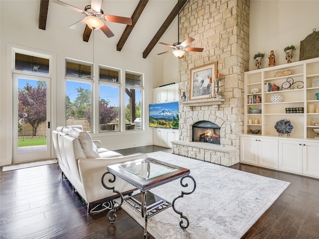 living room featuring high vaulted ceiling, beamed ceiling, dark hardwood / wood-style flooring, and a stone fireplace