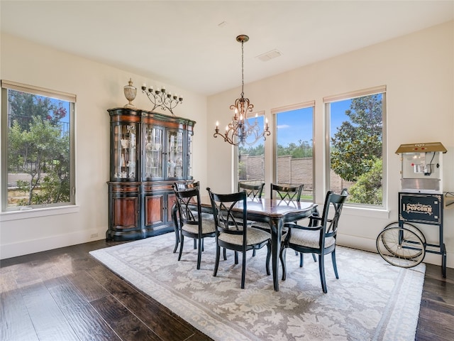 dining room with dark wood-type flooring, a notable chandelier, and a healthy amount of sunlight